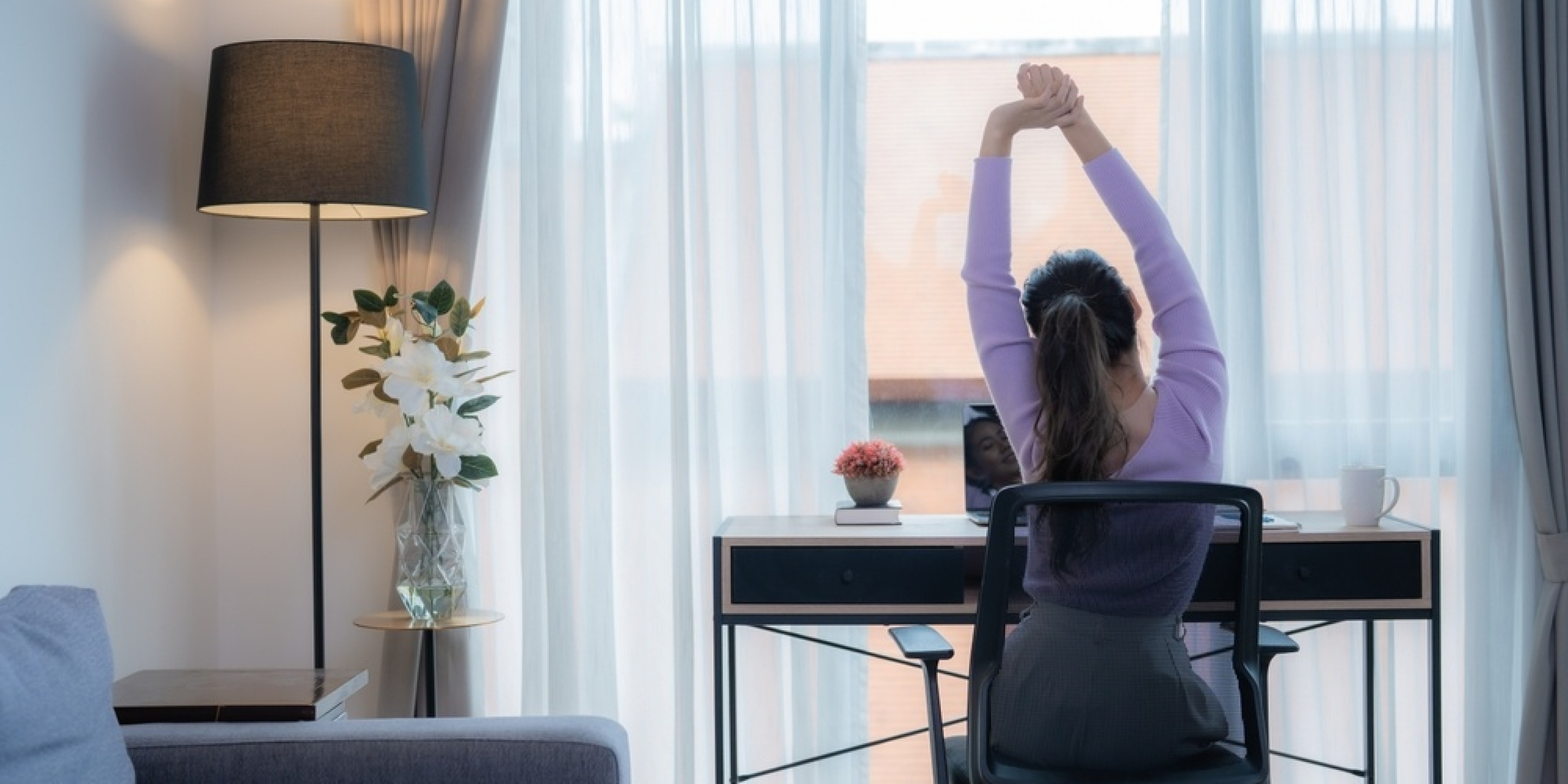 ผู้หญิงกำลังนั่งยืดเส้นบนเก้าอี้ทำงาน-ดูแลสุขภาพคอ-บ่า-ไหล่